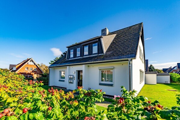 A two-story house with a sloped roof, a front door, and a small porch. - App.syltperle - Helle Wohnung Ruhig Gelegen in Westerland (Sylt)