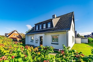 A two-story house with a sloped roof, a front door, and a small porch. - App.syltperle - Helle Wohnung Ruhig Gelegen in Westerland (Sylt)