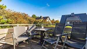 A wooden deck with outdoor furniture, including chairs and a table, under a clear sky. - App.syltperle - Helle Wohnung Ruhig Gelegen in Westerland (Sylt)