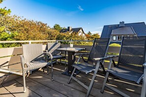 A wooden deck with outdoor furniture, including chairs and a table, under a clear sky. - App.syltperle - Helle Wohnung Ruhig Gelegen in Westerland (Sylt)