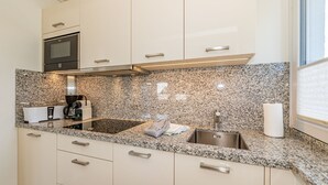 Una cocina moderna con encimeras de granito, electrodomésticos de acero inoxidable y armarios blancos.
