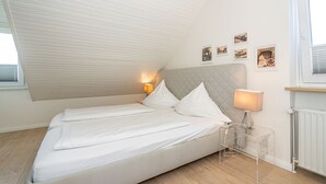 Un dormitorio con cama, lámparas de noche y un radiador.