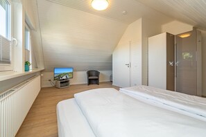 A bedroom with a bed, a TV, a chair, and a wardrobe. - App.syltperle - Helle Wohnung Ruhig Gelegen in Westerland (Sylt)