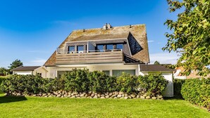 A modern house with a sloped roof, large windows, and a stone foundation. - App.syltperle - Helle Wohnung Ruhig Gelegen in Westerland (Sylt)