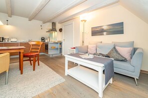 A modern living room with a sofa, a coffee table, and a dining area with a table and chairs.