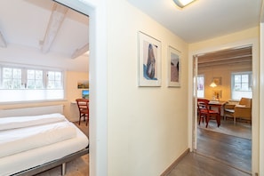 Quarto de hotel com cama, escrivaninha e cadeiras. Há quadros nas paredes e uma janela com persianas.