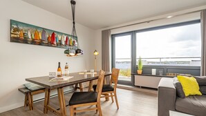 A modern living room with a dining area, large windows, and a view of the water.