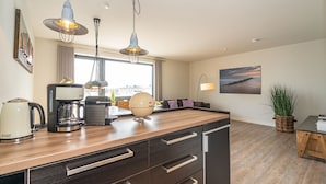 A modern kitchen with a central island, pendant lighting, and a view of the city.