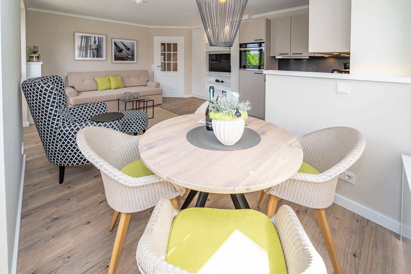 A modern living room with a round wooden table, wicker chairs, and a beige sofa.