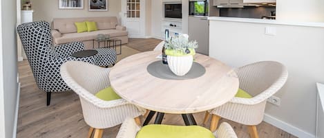 Ett modernt vardagsrum med ett runt träbord, flätade stolar och en beige soffa.
