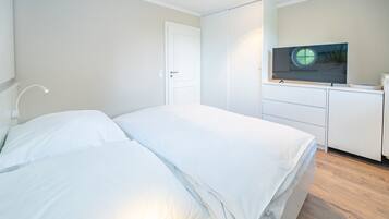 Een slaapkamer met een bed, een bedlampje, een kledingkast en een televisie op een dressoir.