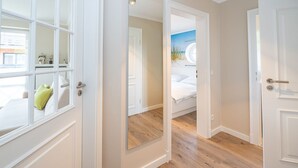 Un couloir aux portes blanches, un mur miroitant et un lit donnant sur le ciel.