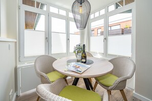 A round table with two wicker chairs, a magazine, and two bottles of alcohol.