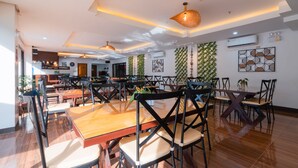 Un amplio comedor con varias mesas y sillas, un equipo de aire acondicionado y decoración en las paredes.