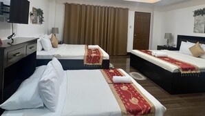 Una habitación de hotel con dos camas, un escritorio, un televisor y una lámpara en el techo.