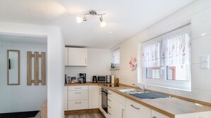 Una cocina moderna con armarios blancos, encimera de madera, horno empotrado y una ventana con cortinas.
