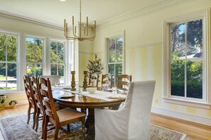 A dining room with a wooden table, chairs, and a chandelier.