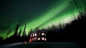 A house with a visible front porch and windows, surrounded by trees. - Gigantic 6b5b home with stunning view & spacious rooms (Fairbanks)