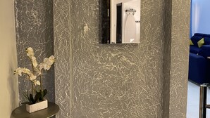 A modern interior with a textured wall, a sign reading "PRAY," a mirror, and a small table with a potted plant. - SECKEBE IMMO ET BUSINESS: SUITE1 (DAKAR)