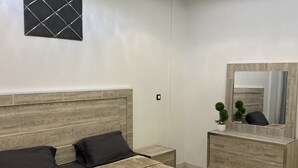 A modern bedroom with a large bed, a wooden headboard, a nightstand, a dresser, and a mirror. - SECKEBE IMMO ET BUSINESS: SUITE1 (DAKAR)