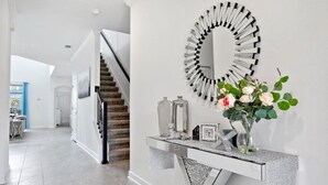 Ein modernes Interieur mit einer Treppe, einem Zier-Spiegel und einer Konsolentisch mit einer Blumenvase.
