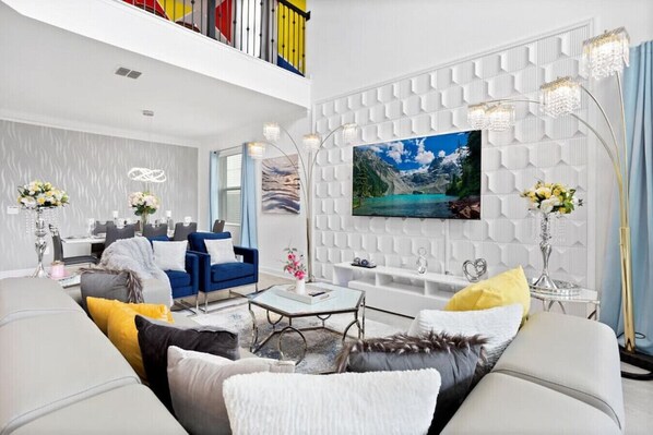 Ein modernes Wohnzimmer mit hoher Decke, einem großen Flachbildfernseher und einer Wand mit weißer Struktur.