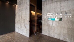 A modern interior with exposed concrete walls and a visible entrance to a bar area. - The Urban Room (Phuket)
