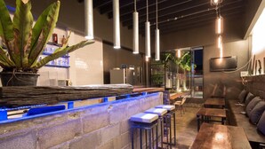 A bar area with a stone counter, blue LED lights, and seating with stools and benches. - The Urban Room (Phuket)