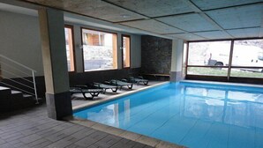 An indoor swimming pool with clear glass walls, a stone wall, and a tiled floor. - 2 Rooms 4 people Swimming Pool (VALLOIRE)