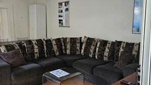 Un salon moderne avec un canapé d’angle, une table basse et un ventilateur de plafond.