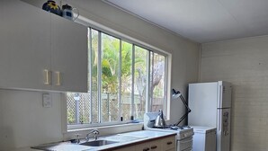Une cuisine moderne avec des meubles blancs, un évier, une cuisinière et un réfrigérateur.