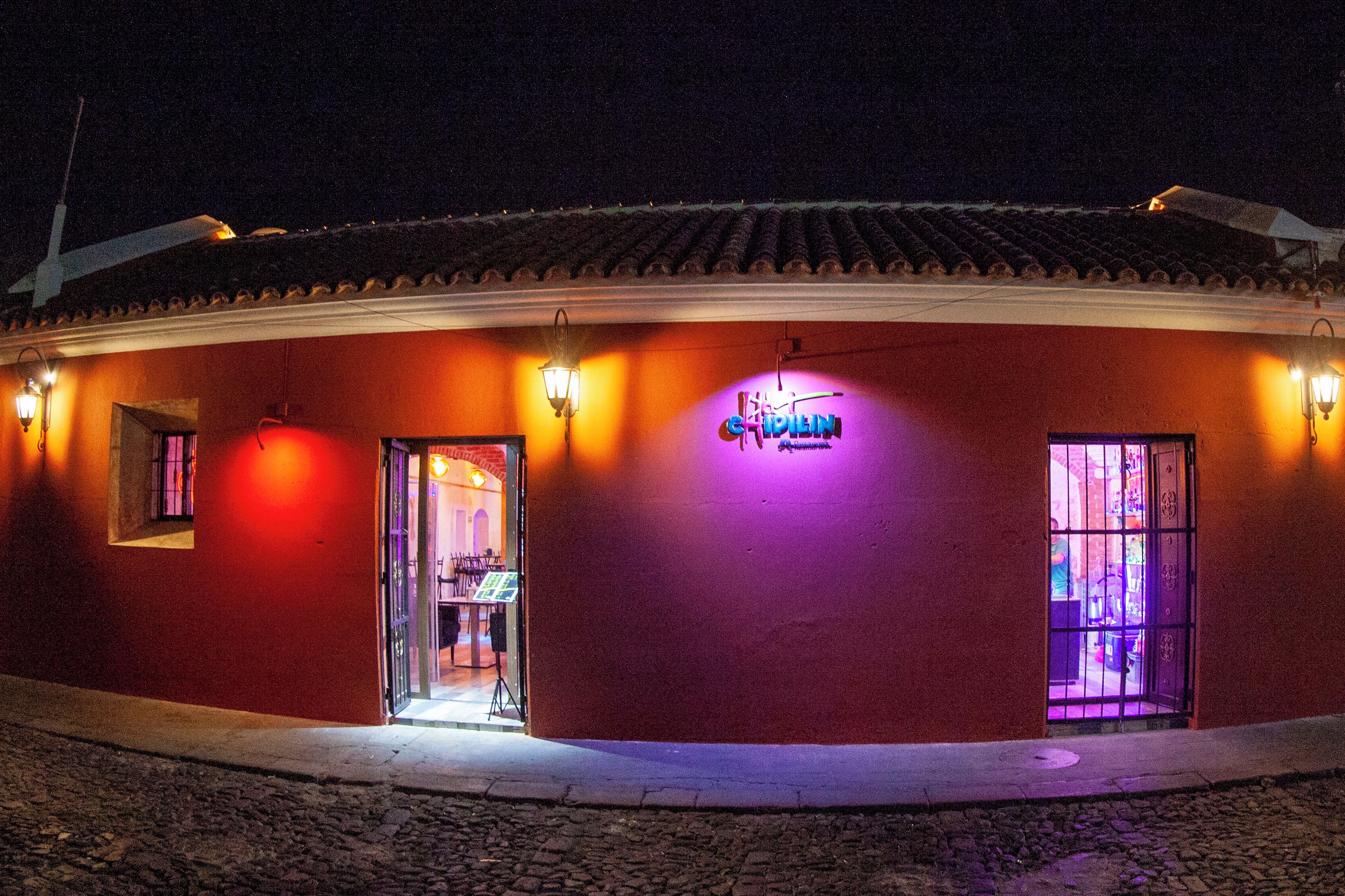 A building with a red facade, a visible entrance, and a neon sign.