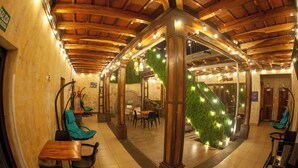 A spacious indoor area with wooden beams, green walls, and a staircase with illuminated steps. Tables and chairs are arranged for seating.