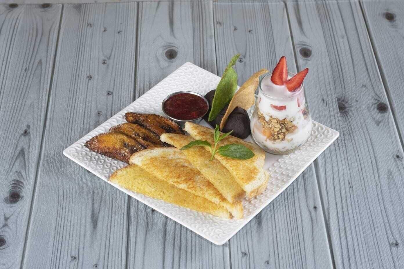 A plate of food with bread, fruit, and a drink on a textured white plate.