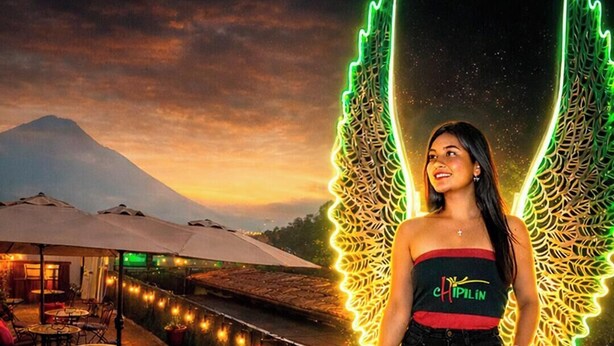 A person standing on a terrace with a mountain in the background, wearing a top with "CHIPLIN" on it.