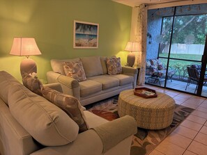 A living room with a sofa, two armchairs, a coffee table, and a painting on the wall.