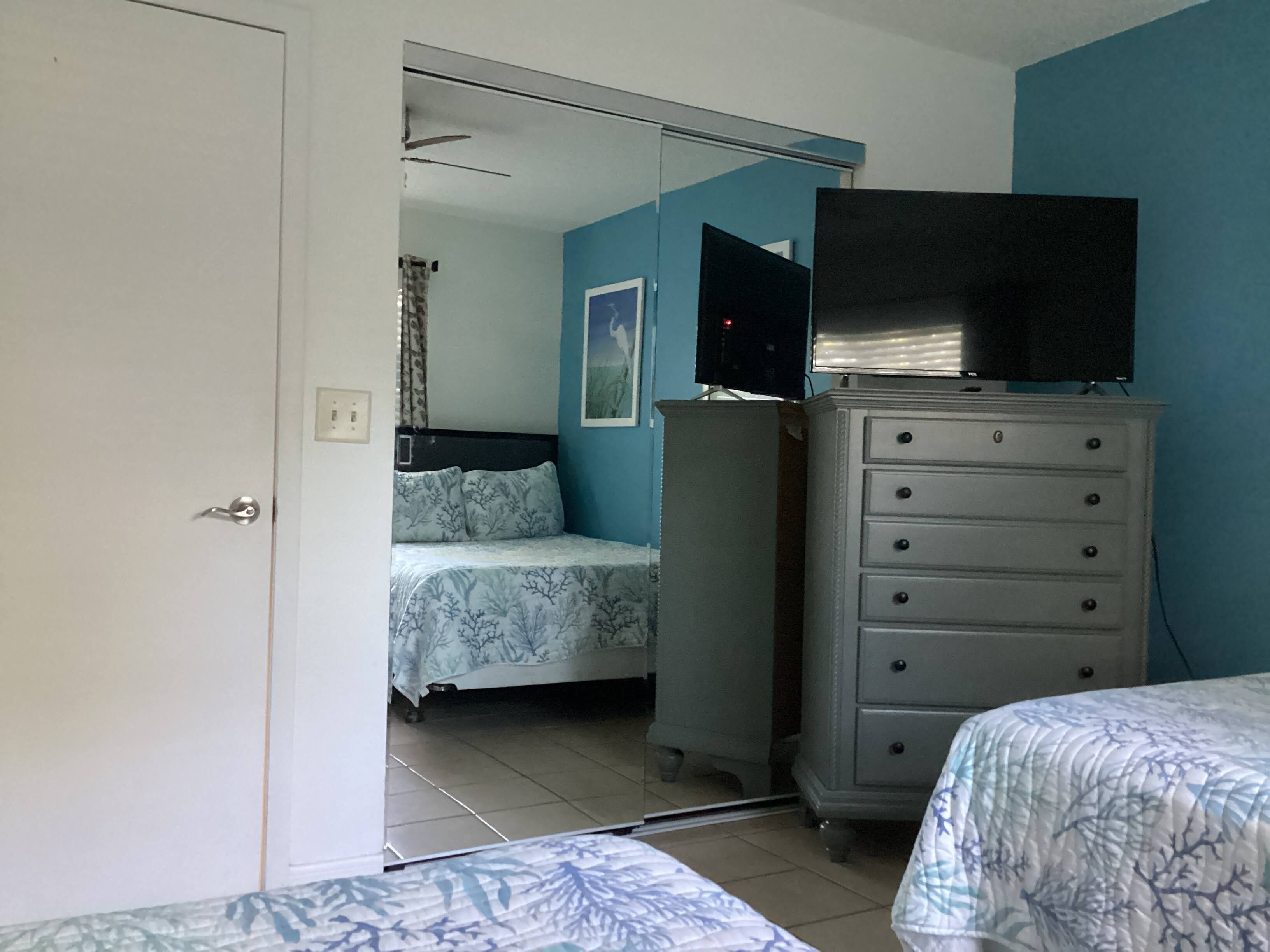 A bedroom with a bed, dresser, and a television on a stand.