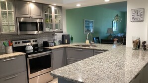 Cocina moderna con encimeras de granito, electrodomésticos de acero inoxidable y una pared de acento color aguamarina.