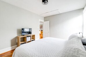 Een moderne hotelkamer met een groot bed, een televisie op een houten standaard, en een deur naar een badkamer.