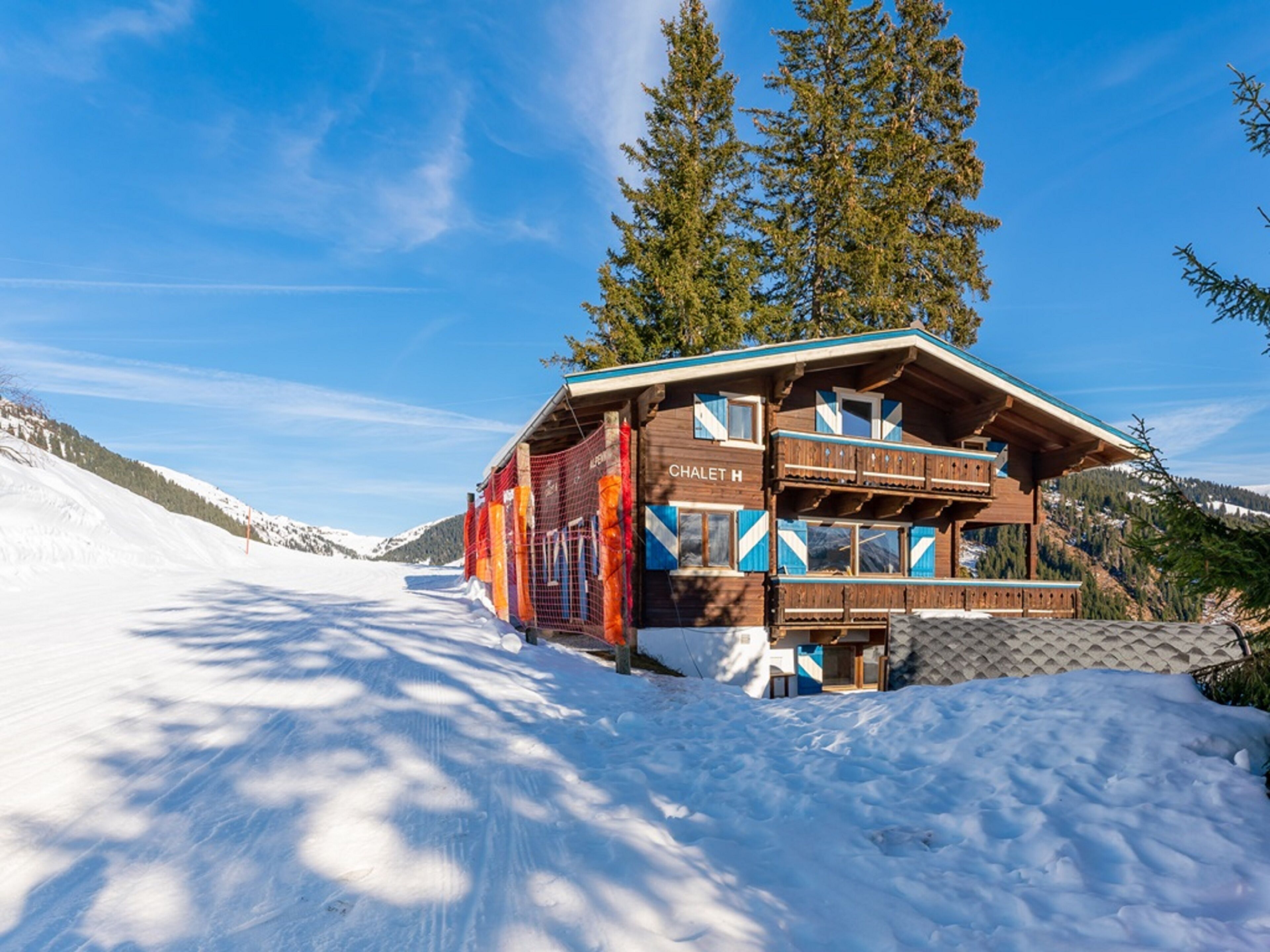 Ein Chalet mit Holzausschau, mehreren Balkonen und einem Schild mit der Aufschrift 'CHALET H'.