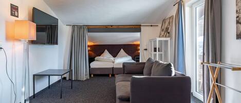 Une chambre d’hôtel de taille réduite, comprenant un lit, un canapé, un bureau et un téléviseur.