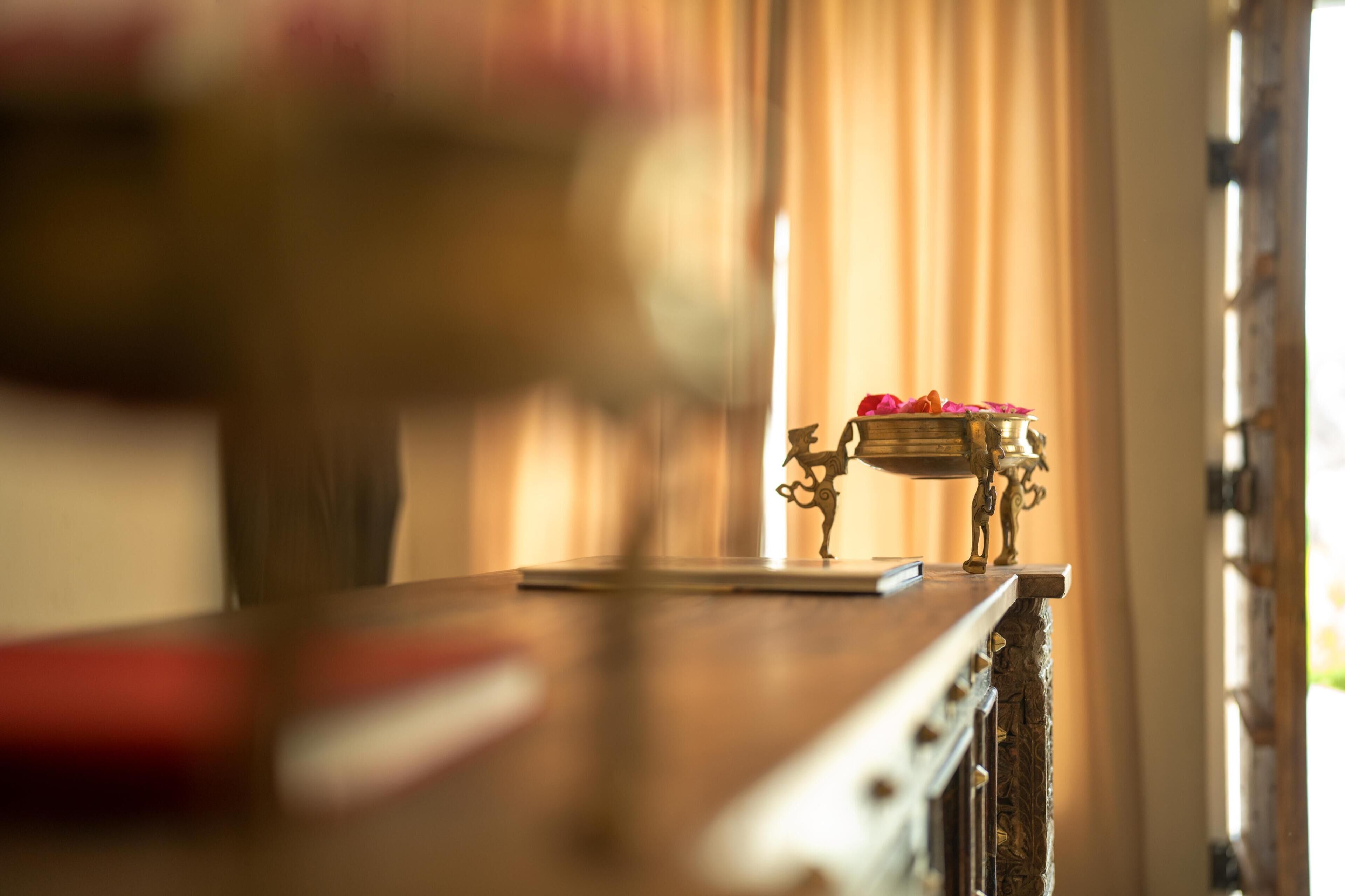 Une vue floue d’une pièce avec une table en bois et un objet décoratif en laiton posé dessus.
