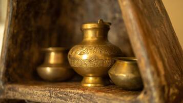 A wooden shelf with three brass bowls of varying sizes.