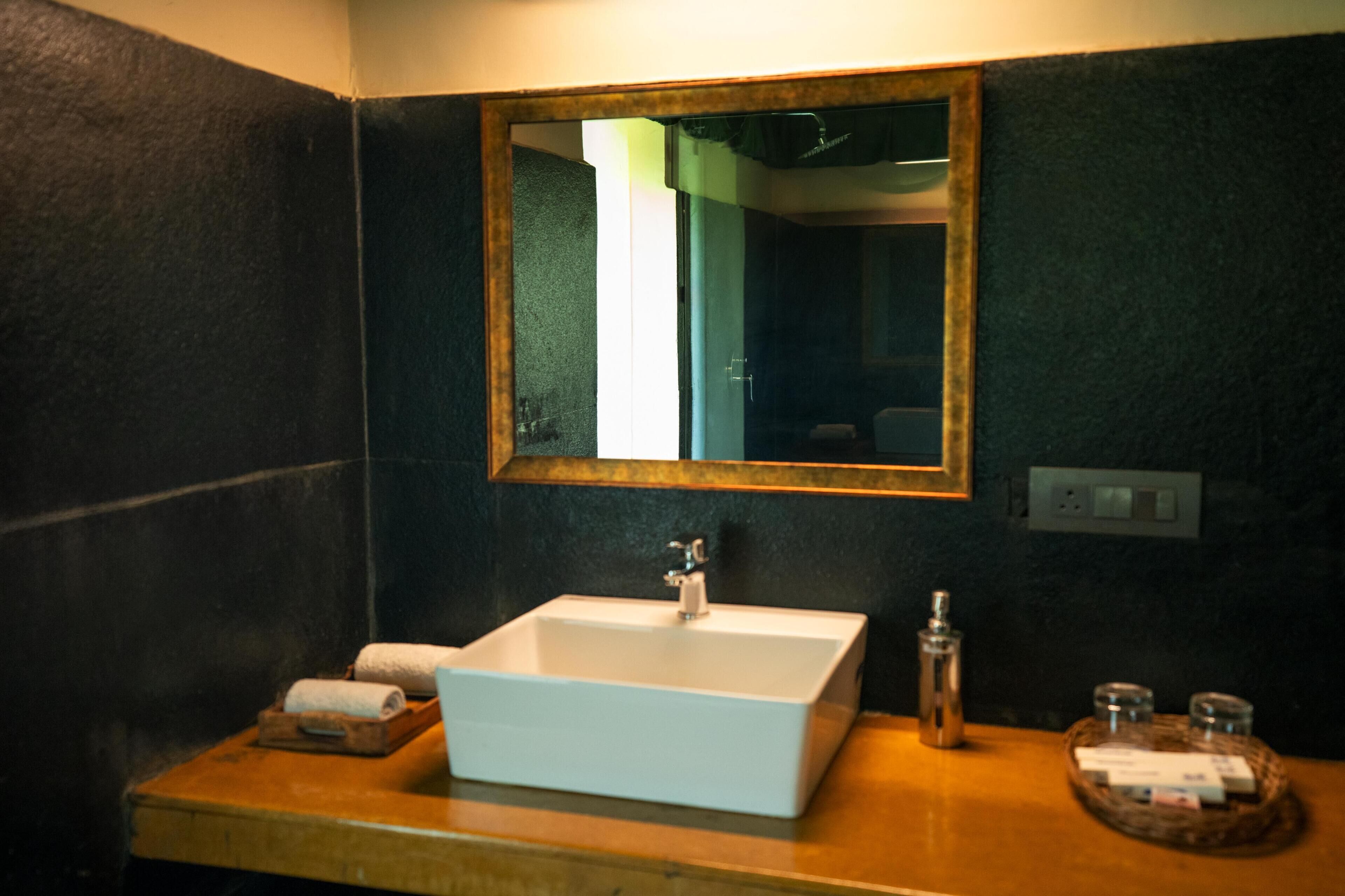 Un baño con un lavabo blanco, un espejo y un mueble de tocador de madera.
