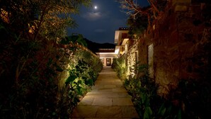 A stone pathway leading to a building with a moon in the sky.