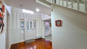 A hallway with white walls, a wooden floor, and a staircase with white railings. - Close to Airport (Hillside)