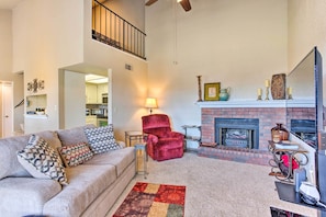 A living room with a fireplace, a red armchair, a beige sofa, and a patterned rug.
