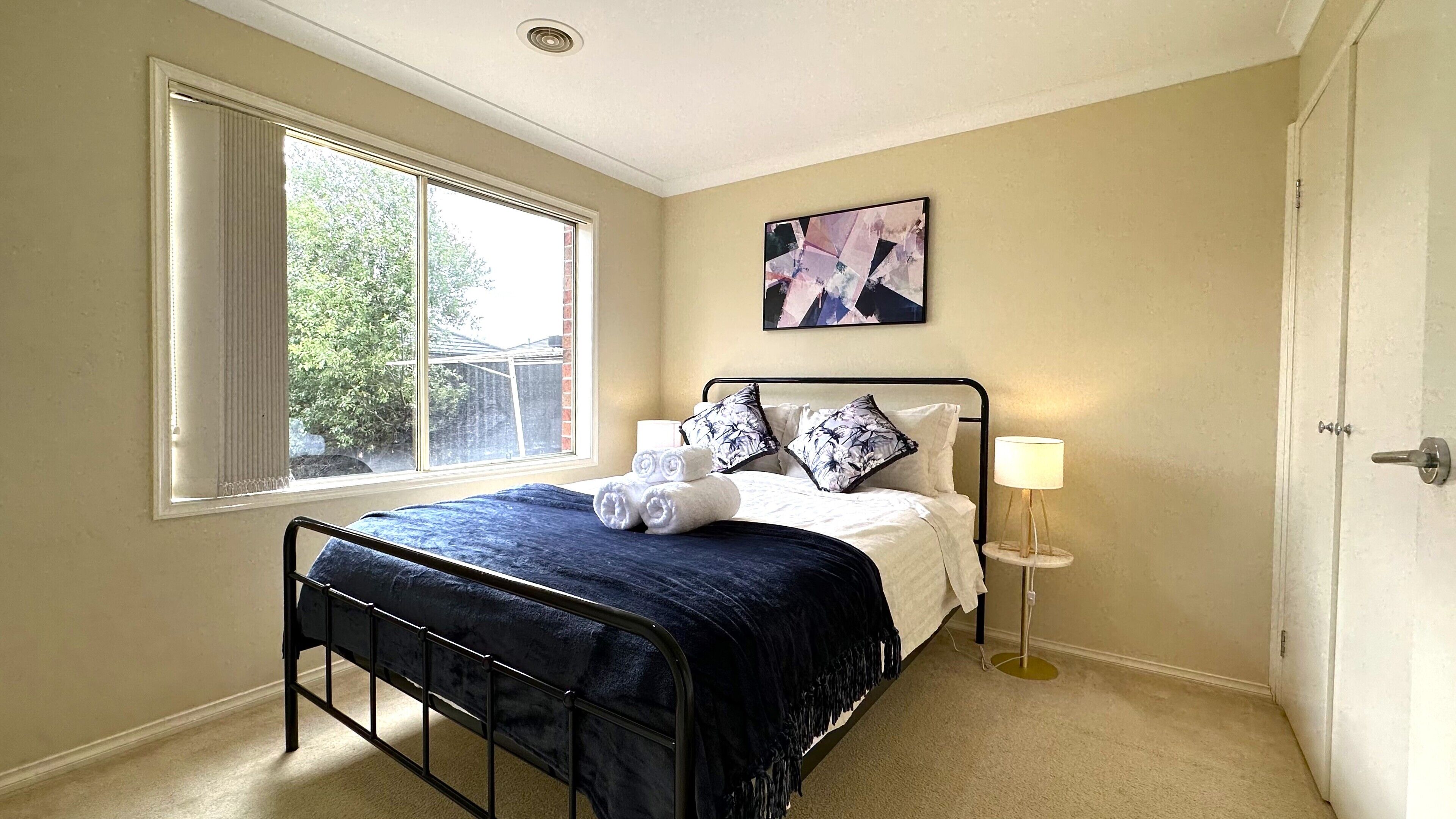A bedroom with a bed, window, and a bedside lamp.
