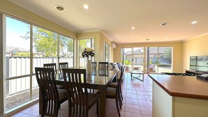 A spacious dining area with a long table and chairs, large windows, and a TV on a wooden counter. - Open Range Zoo/Supper Comfortable Beds/Shopping Center (Point Cook)