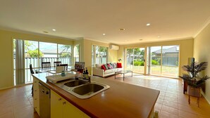 A spacious kitchen with a central island, large windows, and a sliding glass door leading to a backyard. - Open Range Zoo/Supper Comfortable Beds/Shopping Center (Point Cook)